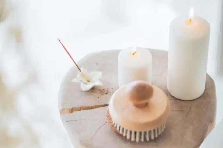 Auf einem Holzstamm stehen 2 Kerzen und eine Bürste für den Spa & Wellnessbereich im Hotel LOISIUM Champagne.