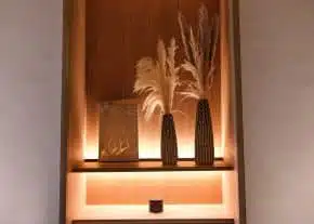 An orange-lit shelf with decorative items in rust brown tones at the hotel LOISIUM Champagne.