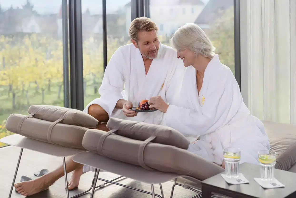 Pärchen in Bademänteln im Spa mit einem Teller Obst